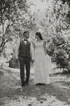 This day is the first of many beautiful days together. The bride and groom are walking along the dirt road, black and white photo