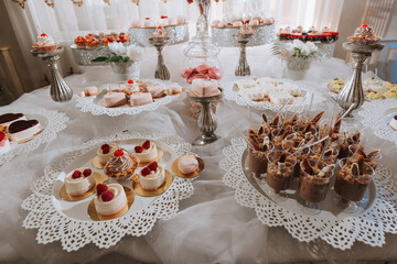Fototapeta na wymiar Festive dessert table with sweets. Wedding candy bar, various cakes, chocolates on stands.