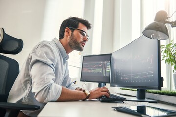 Fototapeta na wymiar Confident businessman. Young bearded trader in formal wear is analyzing trading charts on computer screens while sitting in his modern office