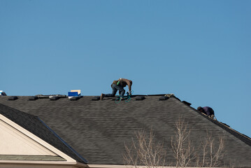 Roofers repairing the roof with new shingles