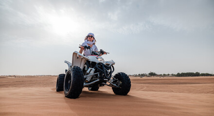 Woman riding sand dunes ATV in the Dubai desert - 626394818