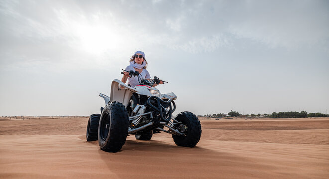 Woman riding sand dunes ATV in the Dubai desert