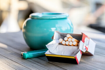 Close-up of cigarettes and a lighter on a wooden table outdoors
