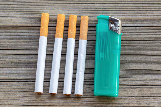 Close-up of cigarettes and a lighter on a wooden table outdoors