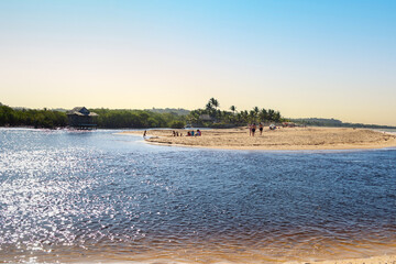 Old fishermen’s house on the river at beautiful sandy beach with palm trees in Trancoso, near...