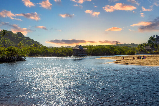 Old fishermen&rsquo;s house on the river at beautiful sandy beach with palm trees in Trancoso, near Porto Seguro, Bahia, Brazil