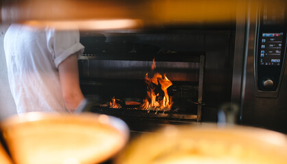 Flames coming up from a grill while cooking in a professional kitchen