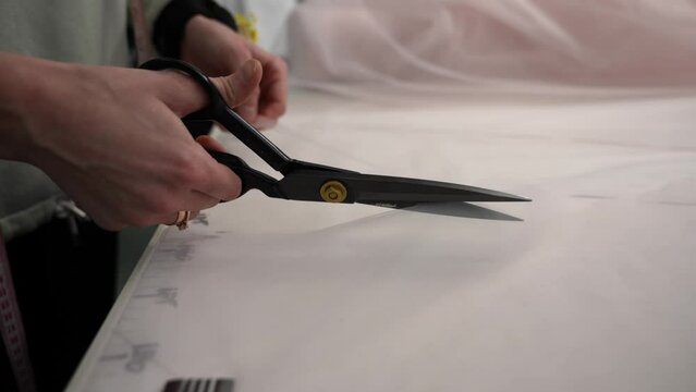 A woman cuts off parts for sewing clothes with scissors