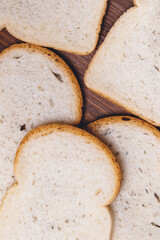 Sliced white bread with brown crust closeup on the dark wooden table. Top view