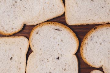 Sliced white bread with brown crust closeup on the dark wooden table. Top view
