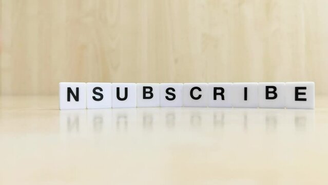 A hand changing the word subscribe to unsubscribe with letters 