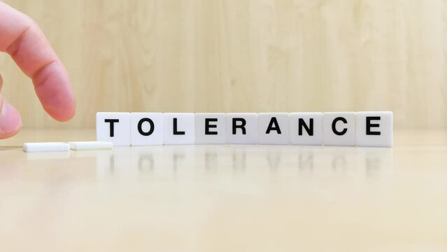 A hand changing the word intolerance to tolerance with letters 