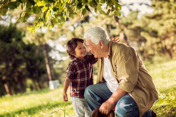 Young boy and his grandfather spending time at the park forest