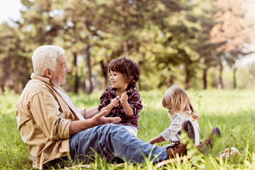 Young boy and girl spending time at the park with their grandfather