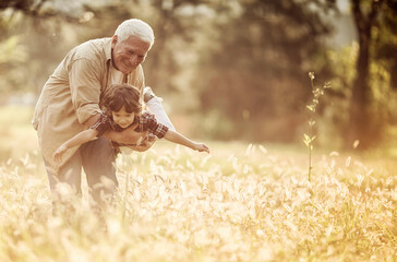 Young boy and his grandfather spending time at the park forest - obrazy, fototapety, plakaty