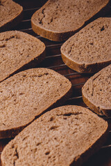 Sliced brown bread on a grill grid on the dark wooden table.