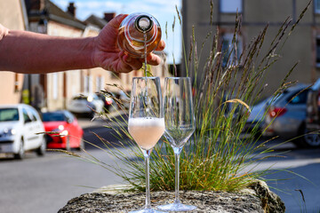 Pouring of premier cru sparkling rose wine with bubbles champagne with view on old houses of...
