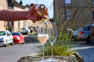 Pouring of premier cru sparkling rose wine with bubbles champagne with view on old houses of...