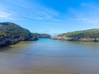 Obraz premium Aerial view on Playa de Poo during low tide near Llanes, Green coast of Asturias, North Spain with sandy beaches, cliffs, hidden caves, green fields and mountains.