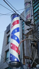 A barber shop pole hanging next to an old, rusty frame in a building