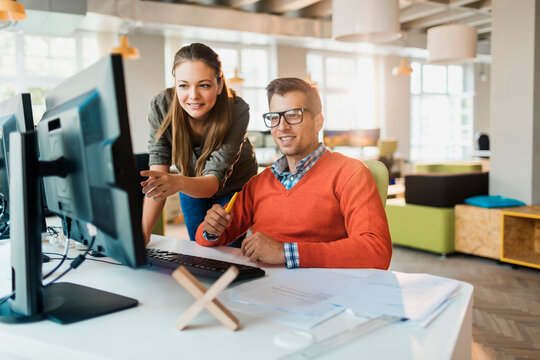 Young man and woman working together on a project on the computer in a startup company office