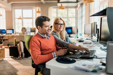 Young man and woman working together on a project on the computer in a startup company office