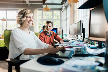 Young man and woman working together on a project on the computer in a startup company office