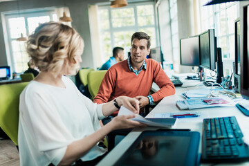 Obraz premium Young man and woman working together on a project on the computer in a startup company office