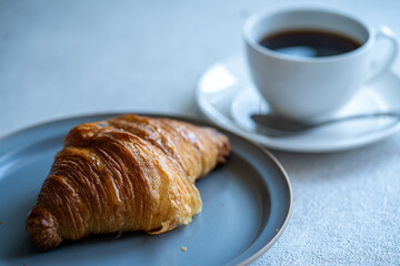 クロワッサンと白いカップに入ったコーヒー