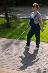 Blind pregnant woman walking in the park with a cane. 