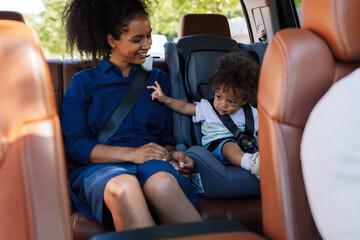 Young smiling mother and her little son sitting together in the backseat of a taxi