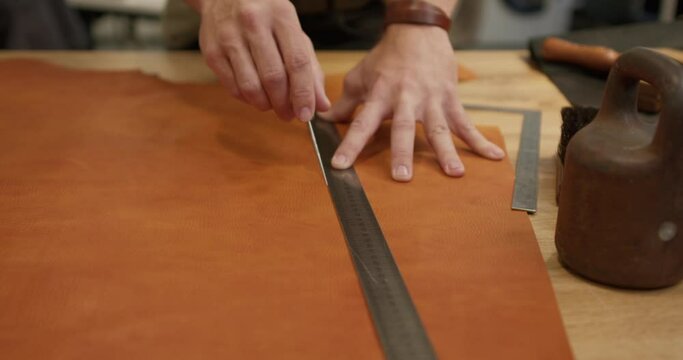 male tailor using measuring tape and scratch awl while making handmade leather goods at workshop Slow motion, job profession occupation, leather-crafting, small business to create leather products.