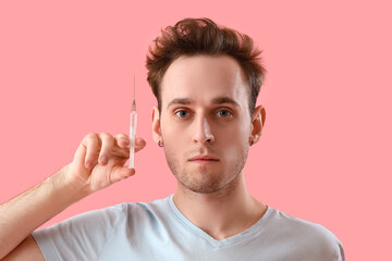 Obraz premium Young man with injection for hair growth on pink background, closeup