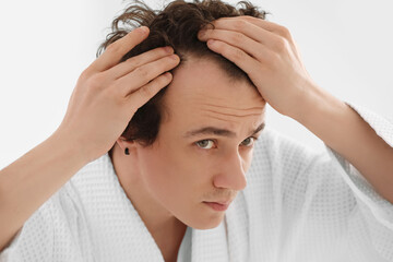 Young man with hair loss problem in bathroom, closeup