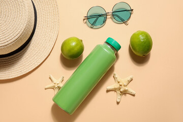 Bottle of soda with beach accessories and lime on beige background