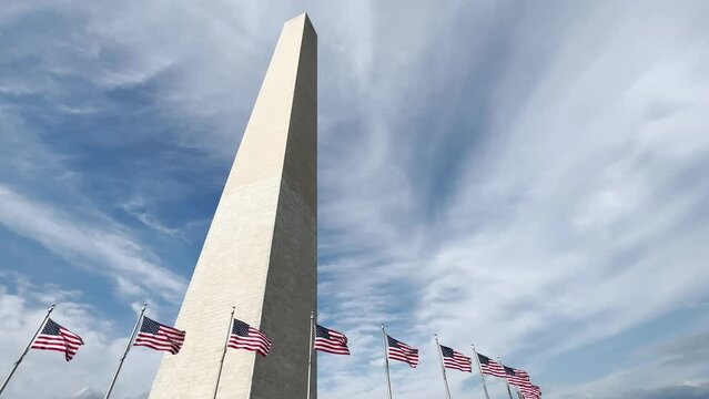 A wide slow motion view of the Washington Monument with the American Flags blowing in the wind.  	