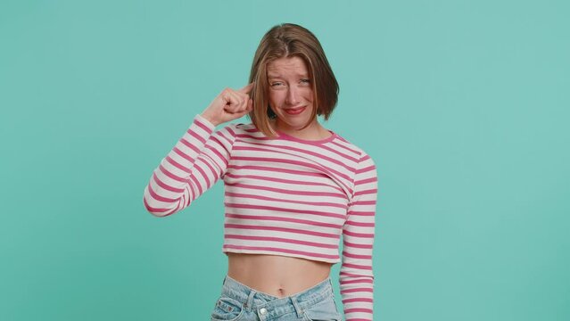 You are crazy, out of mind. Displeased woman pointing at camera, show stupid gesture finger near head, blaming some idiot for dumb insane plan idea, senseless talk. Girl isolated on blue background
