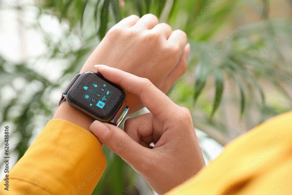 Poster woman setting smart home control system via smartwatch indoors, closeup. app interface with icons on