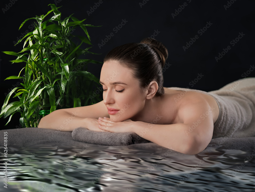 Wall mural Beautiful young woman relaxing in spa salon. Green bamboo stems on background