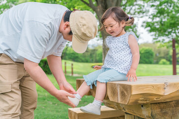 公園で靴を直す親子・靴を履かせるパパ
