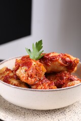 Delicious stuffed cabbage rolls cooked with tomato sauce in bowl, closeup. Space for text