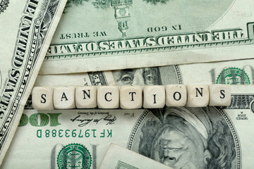 Word SANCTIONS on dollar banknotes, closeup