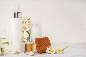 Set of cosmetic products, hair comb and beautiful jasmine flowers on light background