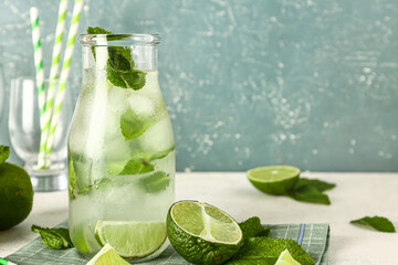 Bottle of cold mojito, mint leaves and limes on light table