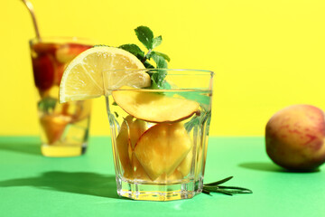 Glasses of fresh peach lemonade with mint and rosemary on colorful background