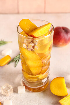 Glass of fresh peach lemonade on white table