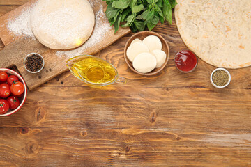 Raw dough, crust and ingredients for preparing pizza on wooden background