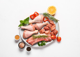 Plate with different raw meat, herbs and spices on light background