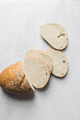 slices of artisan bread loaf, sesame coated bread slices on a marble tray, sandwich bread slices on a tray