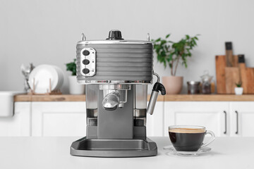 Modern coffee machine with glass cup of hot espresso on table in kitchen
